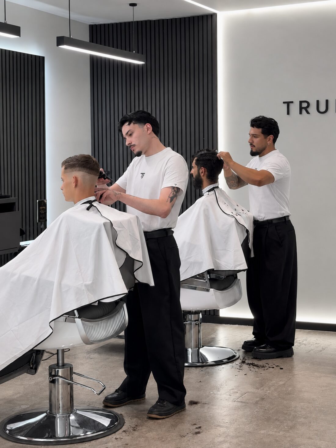 Dois barbeiros a trabalhar lado a lado na sala da True Shape